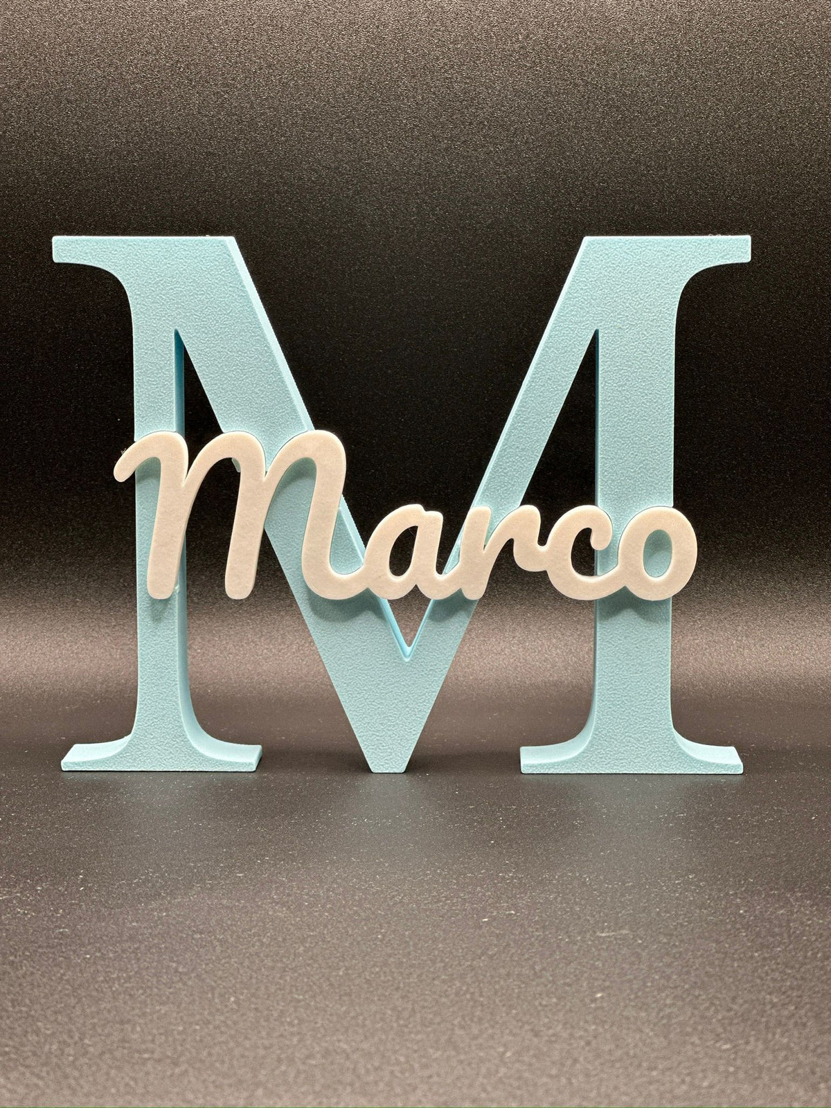 Lettera 3D M azzurra con il nome Marco in corsivo